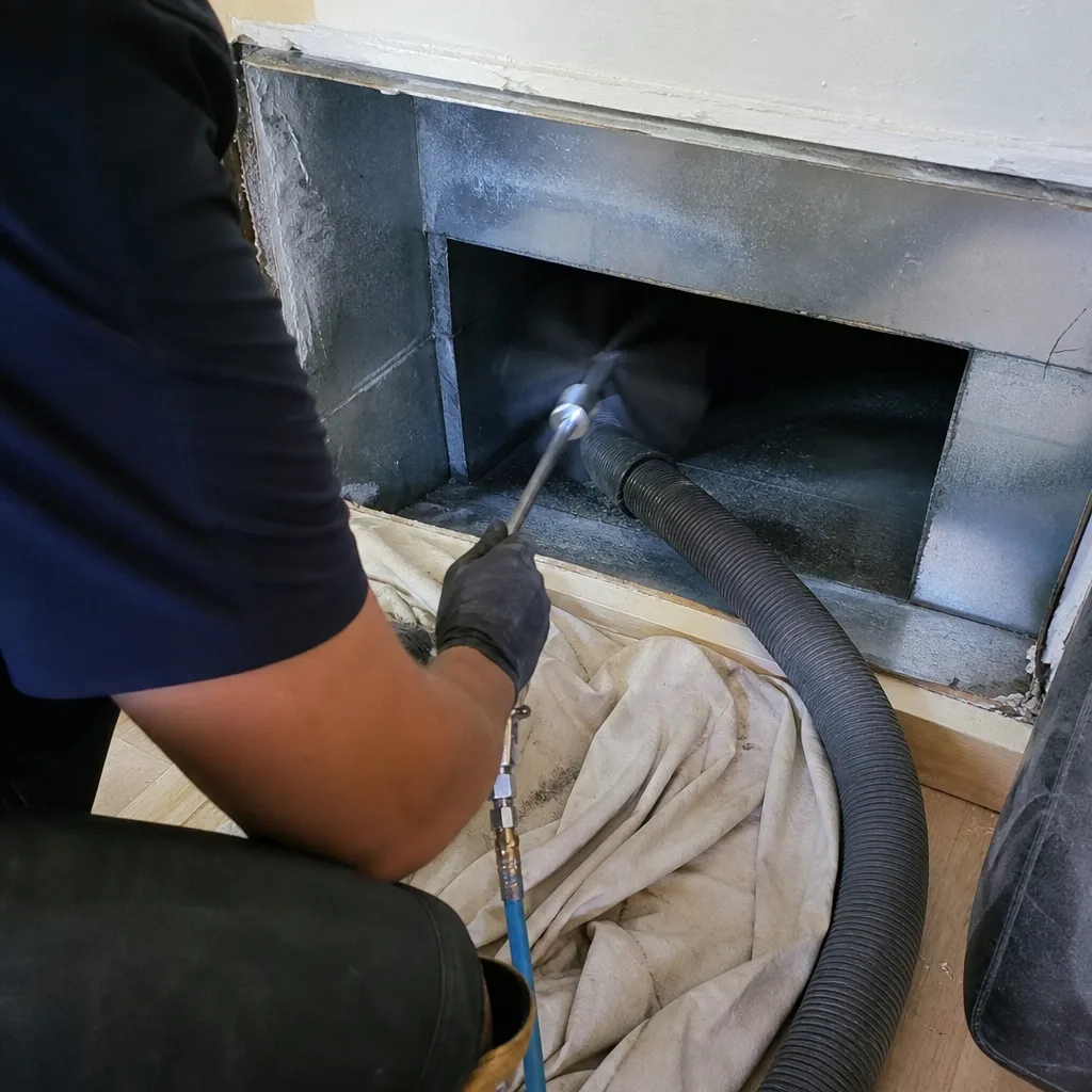 Professional technician performing air duct cleaning with vacuum equipment